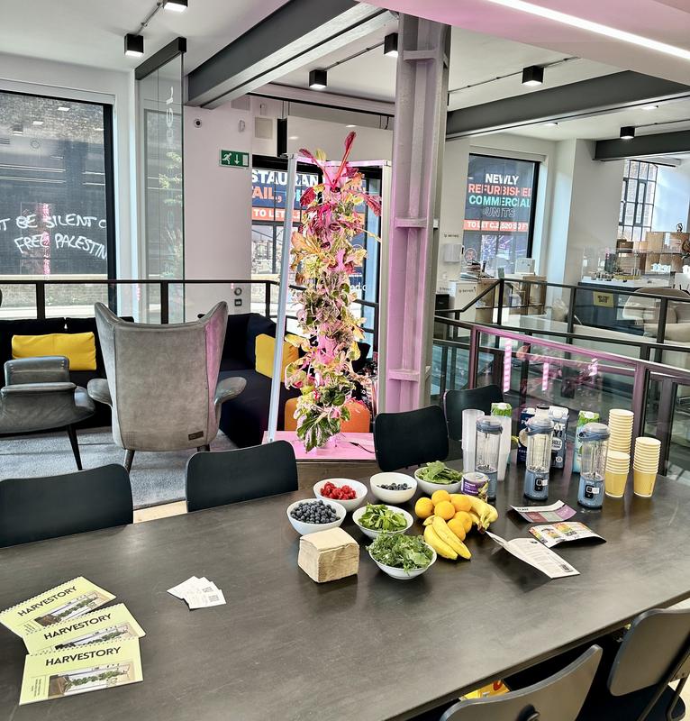 A Harvestory smoothie tasting table in a bright venue beside a growing tower